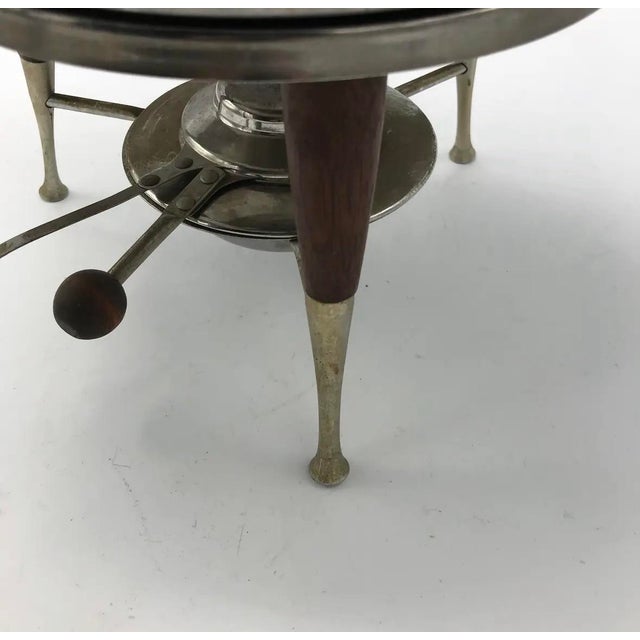 A striking example of American Mid-Century Modern entertaining design, this sculptural stainless steel and teak chafing...