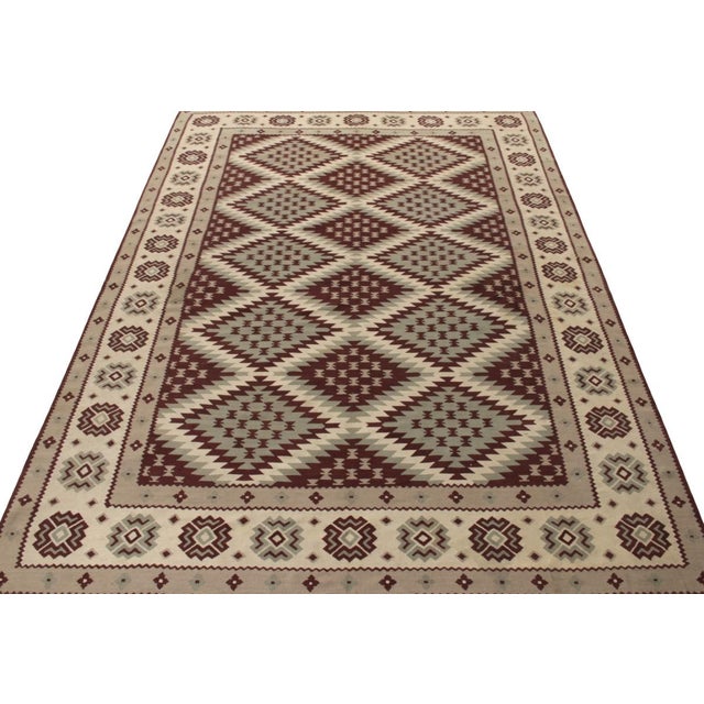 Originating from Turkey circa 1950-1960, a sharp vintage kilim rug featuring a neat geometric pattern with tribal motifs...