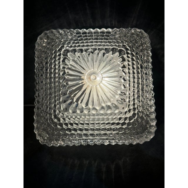 Vintage ceiling light from the 1970s made of thick pressed glass with a decorative geometric texture. Mounted on a black...