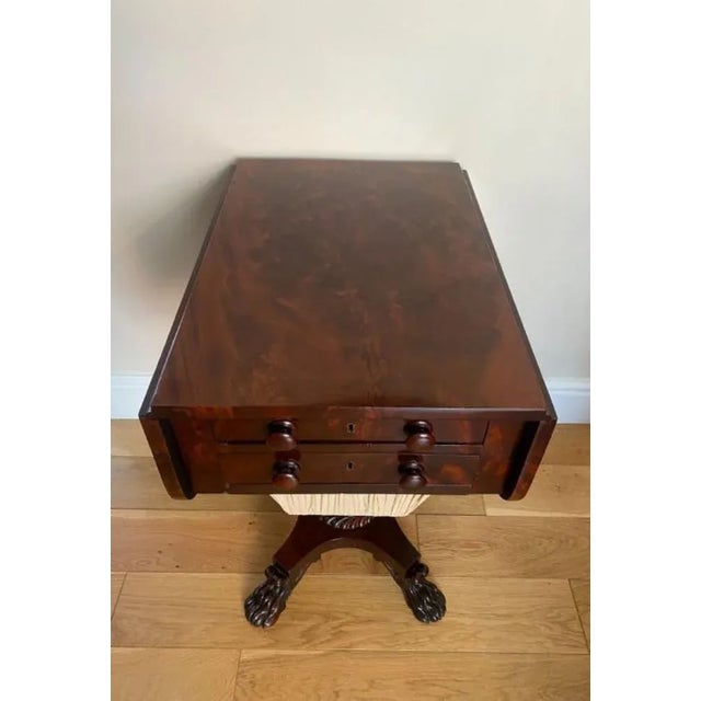 Antique regency quality figured mahogany sewing table having a quality figured mahogany top with two drop leaves above two...