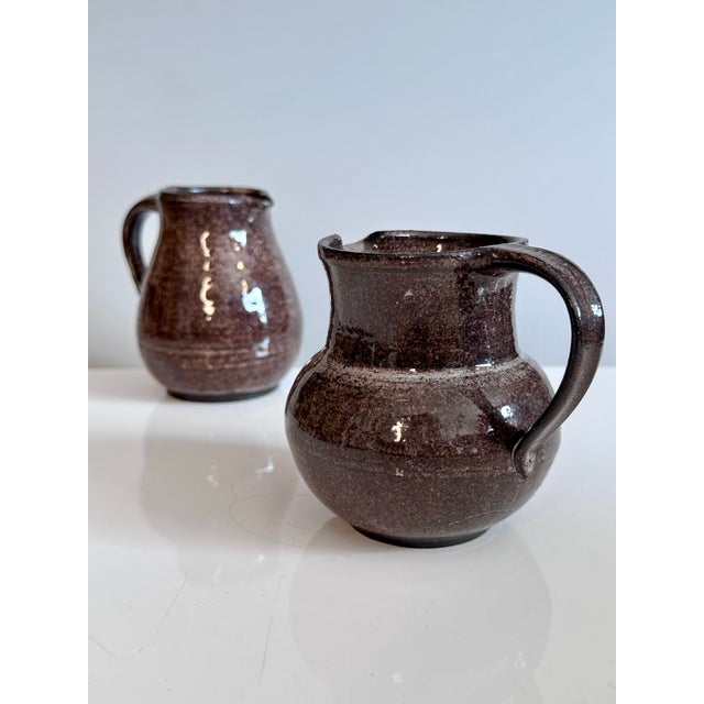 A pair of handcrafted jugs from the Serocka workshop, finished in their characteristic speckled brown and natural glazes...