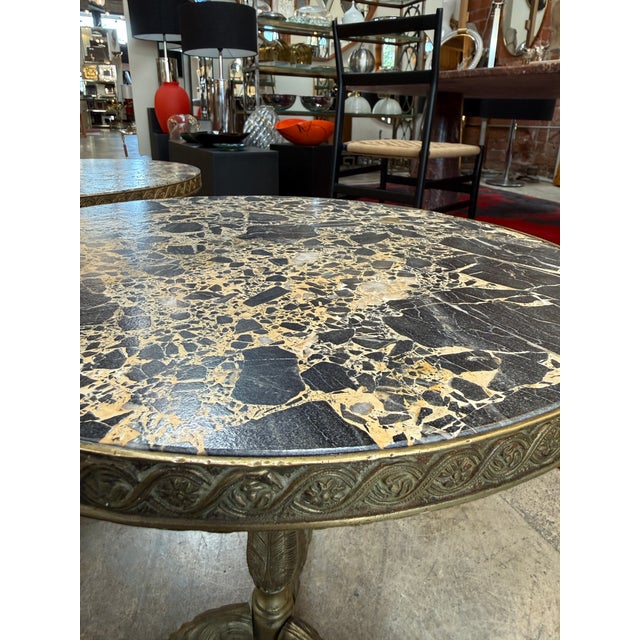 A refined pair of 1970s Italian side tables featuring richly patterned Portoro-style marble tops set on ornate cast-brass...