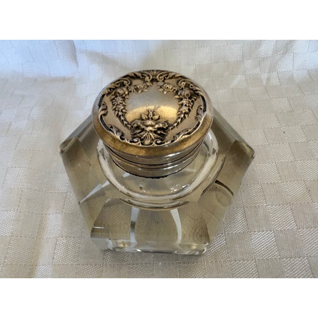 A heavy 6 sided glass inkwell, with a sterling repousse hinged top. The piece is marked with a flag and the word....