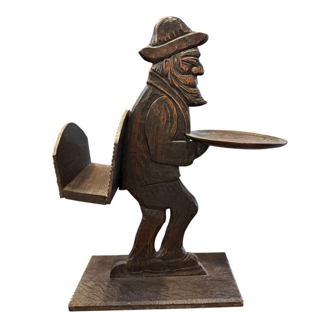 Black Forest/Alpine folk-art carving. It features a bearded man holding a flat circular tray out in one hand, with a...