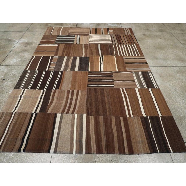 This Mid-20th century Turkish Flatweave Kilim rug, measuring 8' 6" x 12' 11", showcases a captivating patchwork design...