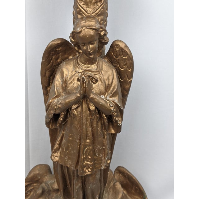 A striking monumental Gothic Revival pedestal candleholder featuring a beautifully modeled praying angel standing above a...