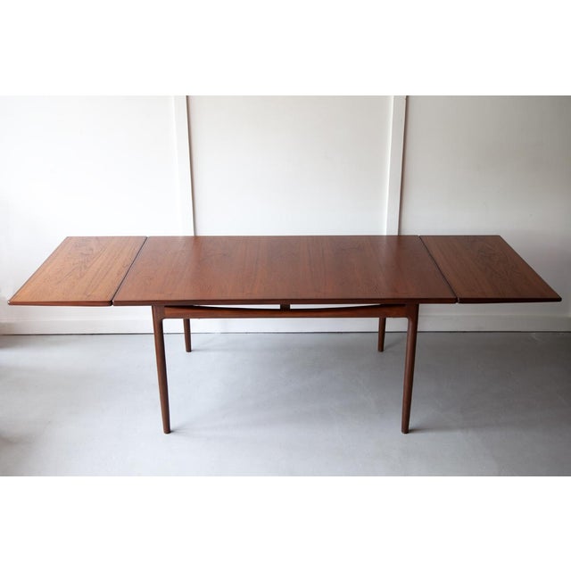 An extending teak dining table, designed by Ib Kofed-Larsen with a beautiful sculptured apron and elegant tapered legs,...