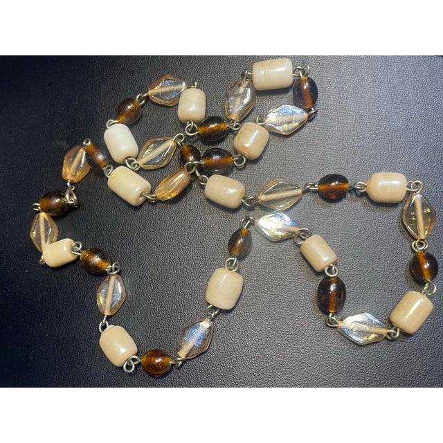 This mid-century Bohemian glass necklace features an alternating sequence off-white to cream-colored translucent...