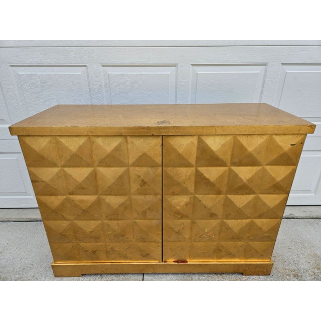 A beautiful diamond pattern gold leaf cabinet or credenza by Barbara Barry for Baker Furniture. This piece features a...