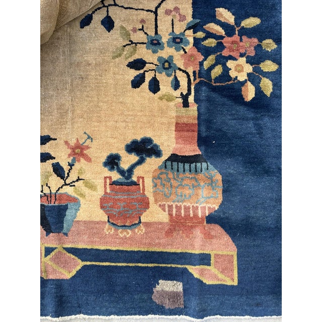 This hand-knotted rug boasts a rich red hue framed by lush green borders, creating a captivating contrast. The intricate...