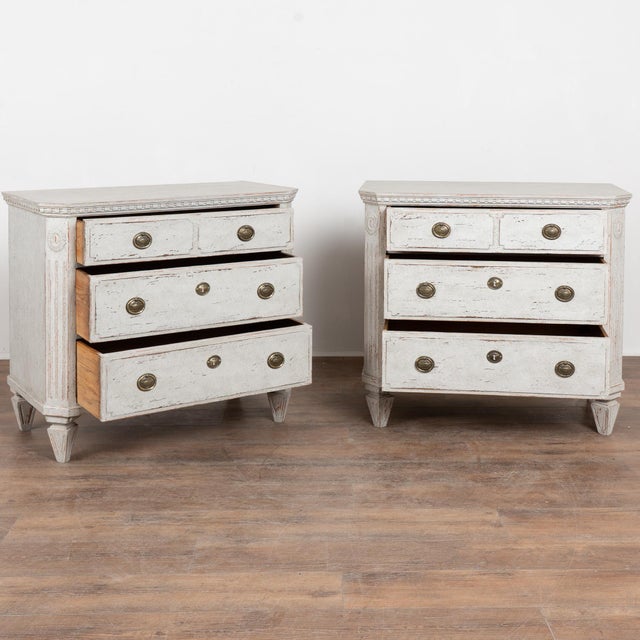 Pair of 19th-century Swedish Gustavian chests of three drawers crafted in pine. Each chest features a newer layered gray...