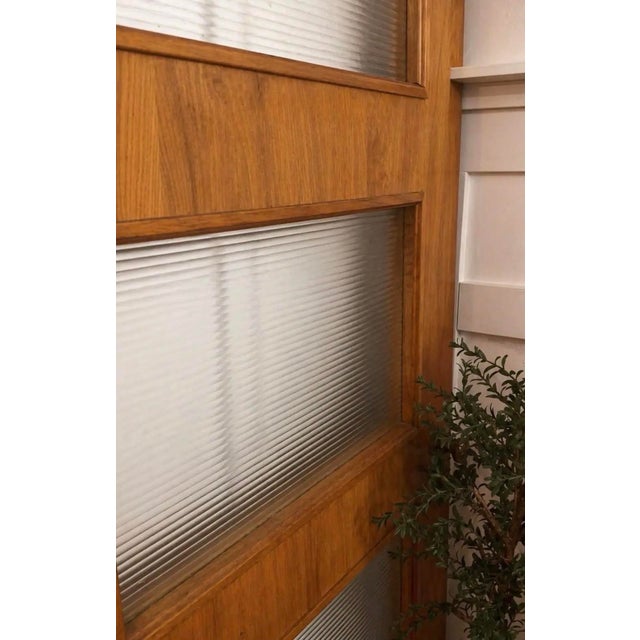 Mid-century paneled wood interior door featuring reeded glass inserts and warm grain. Subtle, age-appropriate wear...