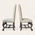 A pair of early–mid 20th century Flemish-style walnut side chairs featuring tall arched backs, robust carved bases, and...