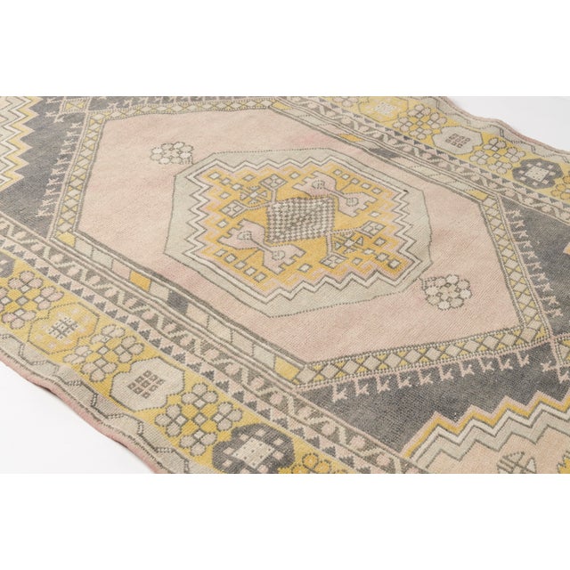 This is a vintage Turkish Oushak rug from the Mid 20th Century. The piece was hand-knotted.