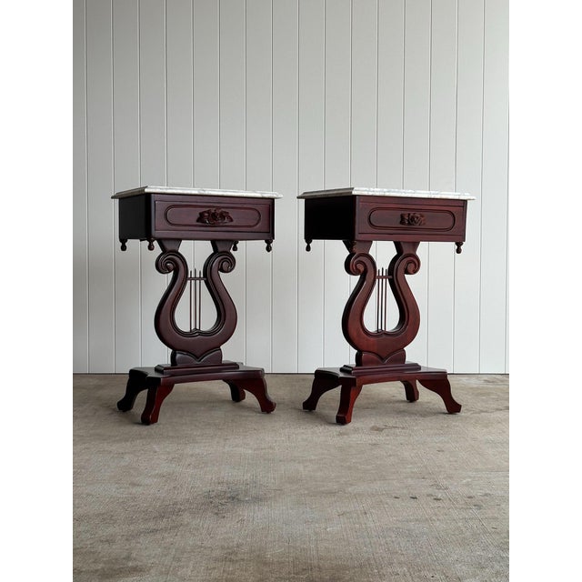 Vintage pair of marble-top end tables with single drawer and lyre-form bases. Solid wood in a deep mahogany finish with...