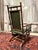A stylish vintage rocking chair with a high backrest and elegant dark green leather upholstery. The deep green tone gives...