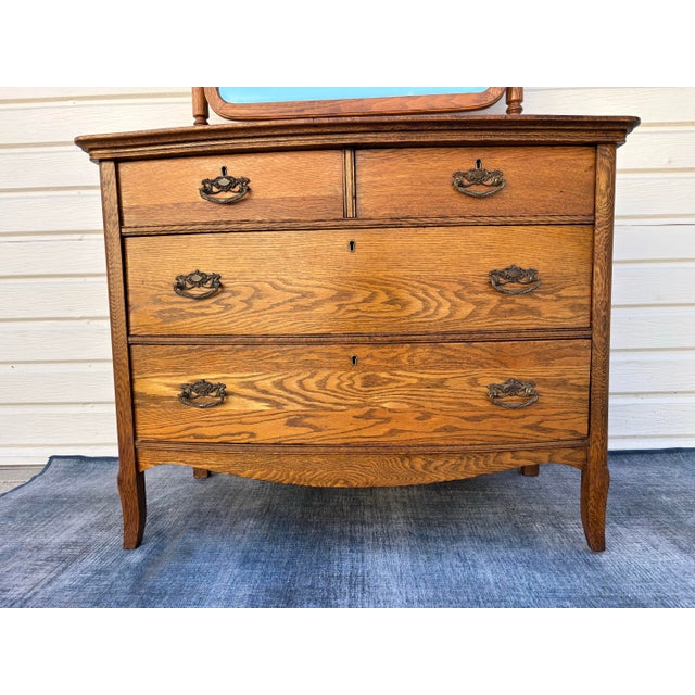 Antique American tiger oak bow-front dresser with a removable beveled swivel mirror. Manufactured by A.H. Heilman &...
