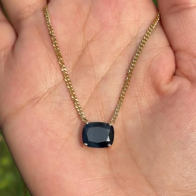 This elegant 5.2 carat cushion cut blue sapphire pendant necklace is crafted in 14K yellow gold. The sapphire measureing...