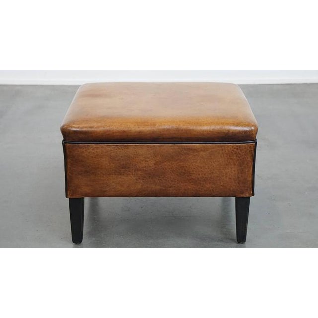 Offered is this beautiful and timeless square sheep leather footstool with black piping. A sheep leather footstool, also...