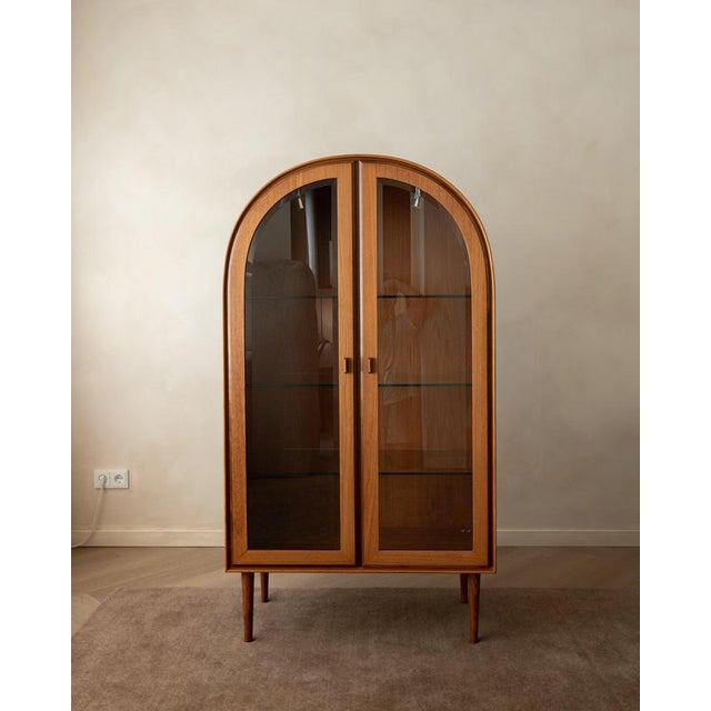 A vintage german arched display cabinet in teak veneer and clear glass, made by brinkmann in germany and estimated to date...