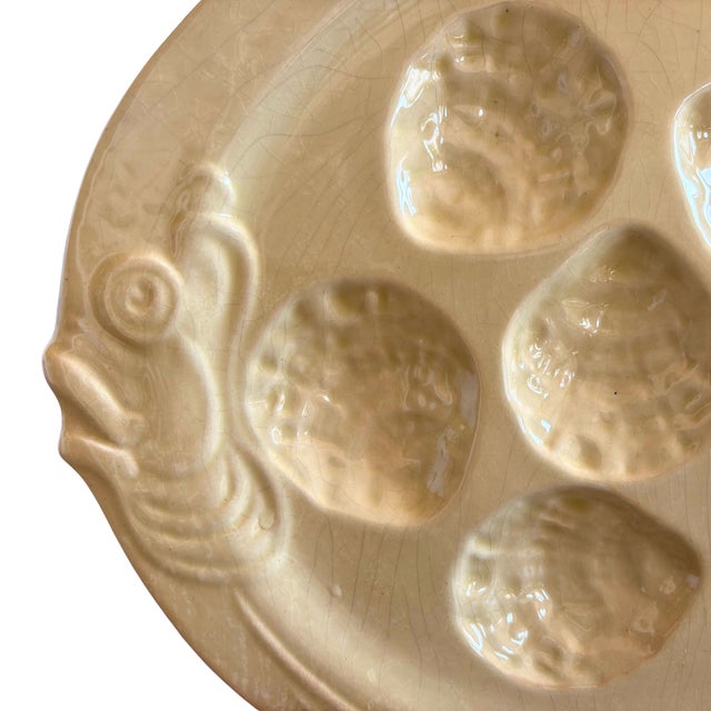 A rare and elegant mid-century French oyster plate in a soft cream glaze, delicately sculpted with six wells and adorned...