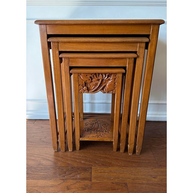This set of four Asian carved wood nesting side tables is believed to date to the 1960s. The front and sides of the three...