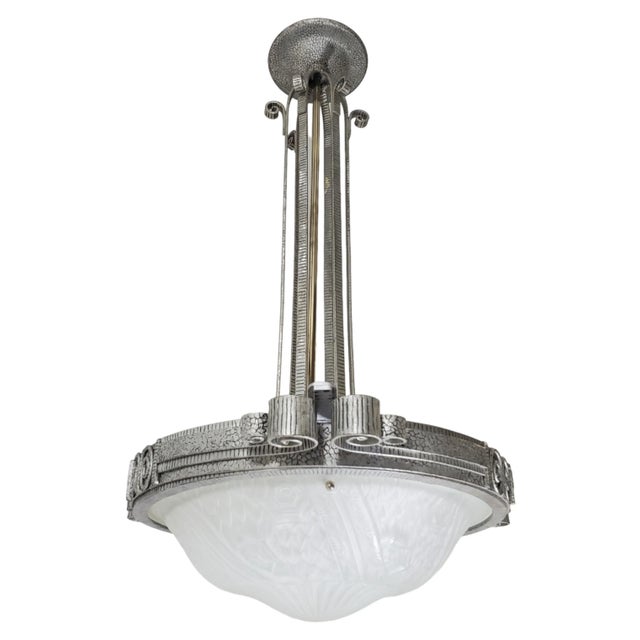 A French Art Deco chandelier, influenced by the Arts and Crafts style, features hand-hammered iron craftsmanship and a...