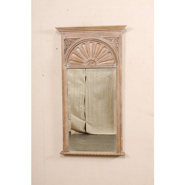 A tall French carved wood trumeau mirror, in fan motif, from the early 20th century. This antique mirror from France...