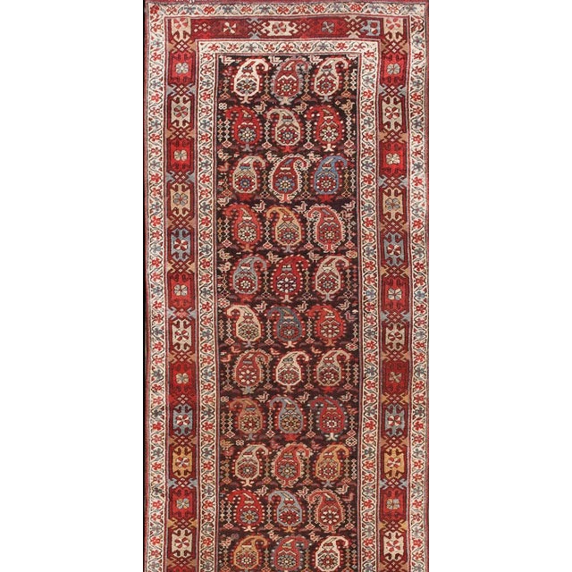 All-over design with rows of boteh and small birds on a brown ground. Interesting main border with linked design elements...