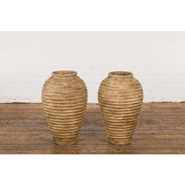 A near pair of vintage Thai storage vases from the mid 20th century with concentric circle design, rustic character and...