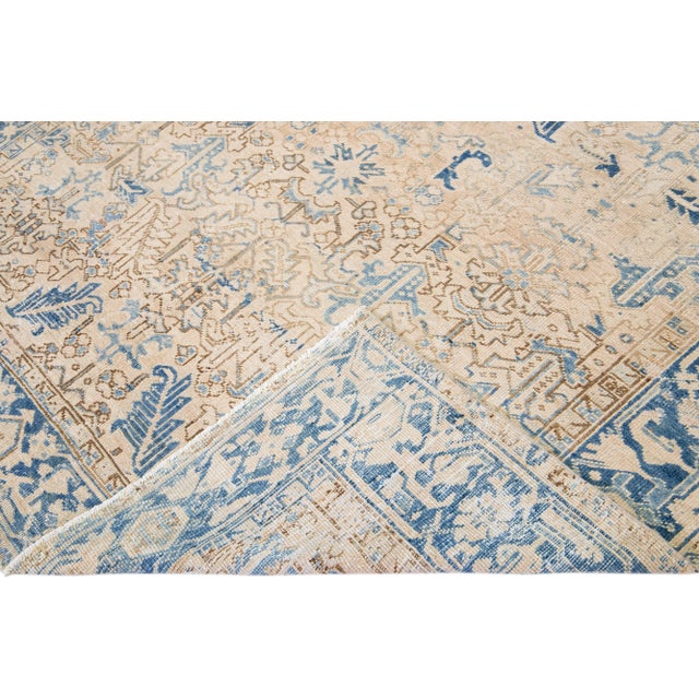 Beautiful antique Heriz hand-knotted wool rug with a beige field. This Persian rug has a blue frame and accents in a...
