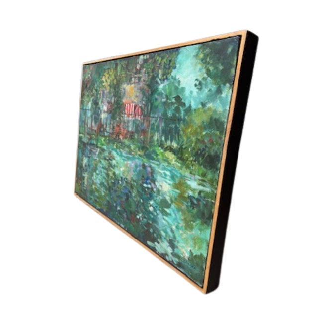 A loosely brushed impressionist acrylic painting of a garden pond, set in a simple oak-toned frame. The reflective water...
