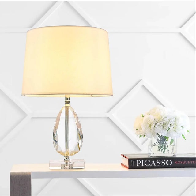 The Trento table lamp features a translucent lucite base accented with brushed silver, allowing light to gently diffuse...