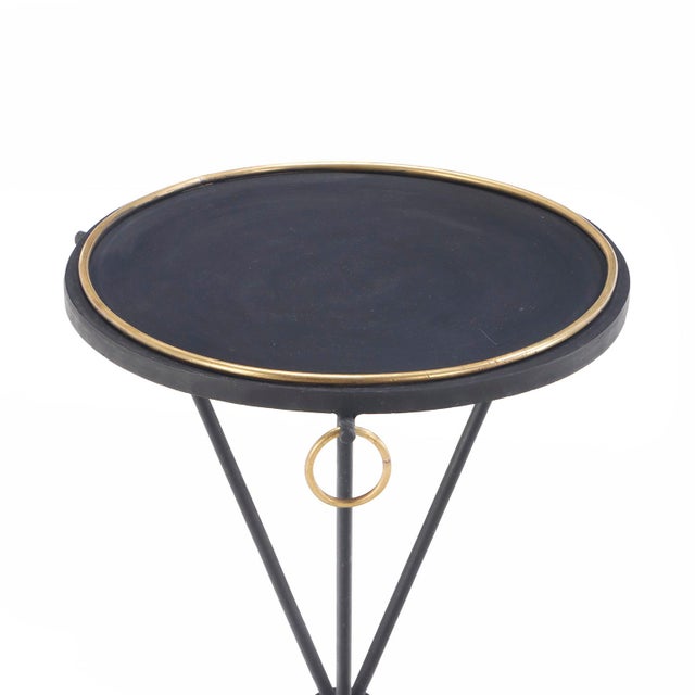 An elegant painted iron drinks table featuring bronze ring detailing encircling the round top and three rings hanging from...
