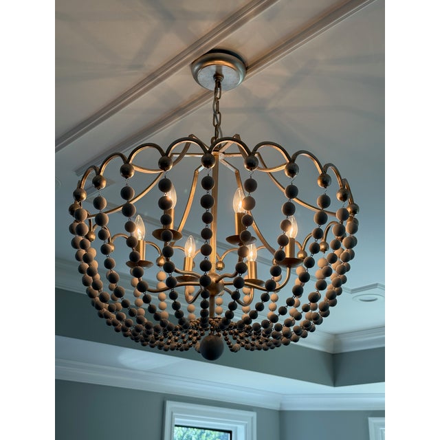 Elegant Peggy chandelier by Gabby featuring a champagne-silver iron frame draped with cascading dove-white wooden beads....