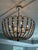 Elegant Peggy chandelier by Gabby featuring a champagne-silver iron frame draped with cascading dove-white wooden beads....