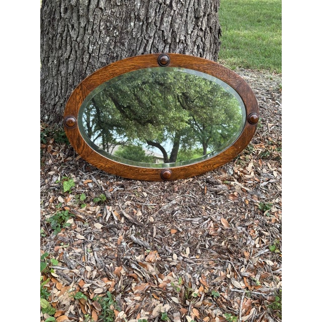 Early 20th Century antique oval oak framed beveled wall mirror with raised circular accents. Dimensions: 30.25" x 19.5"