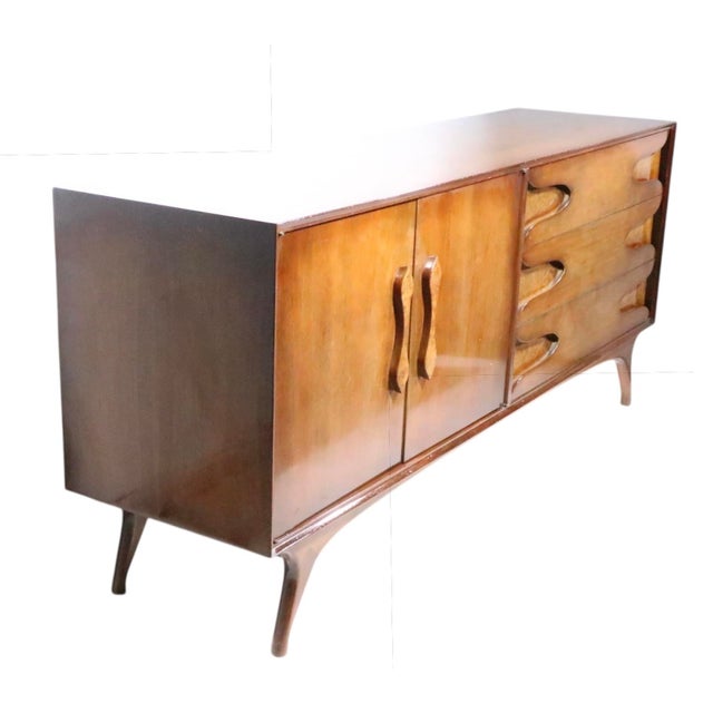 Stylish mod Mid Century dresser having a walnut case with organic sculpted legs, burl fronted door pulls, and burl cut out...
