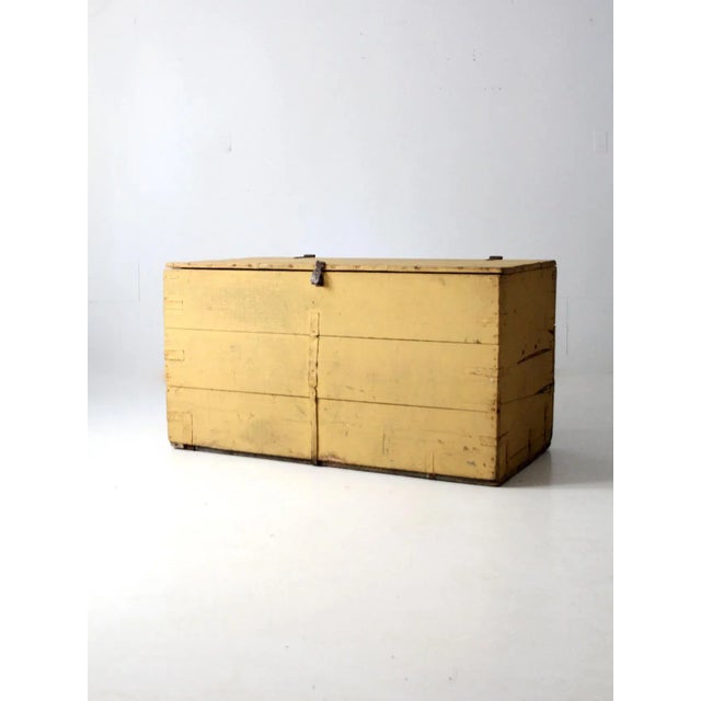 This is an antique blanket chest. The large wooden trunk features mustard yellow paint with iron hardware and a cedar...