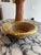 A vintage pencil reed rattan bowl with brass trim, defined by its coiled construction and warm natural tone. The form is...