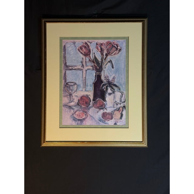 Framed floral still life artwork featuring flowers, fruit, glassware, and a table setting in a classic decorative style....
