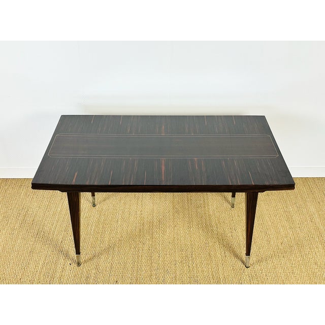 Elegant extendable art deco table, crafted from macassar ebony with exceptional contrasting grain. its tabletop boasts a...