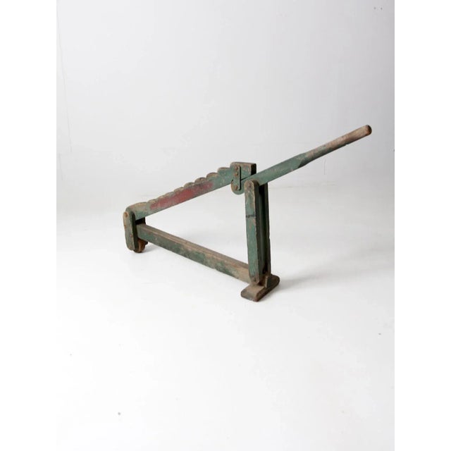 This is an antique wagon jack. The old wooden carriage tool features a stepped bar, a handle lift, and a small front wheel.