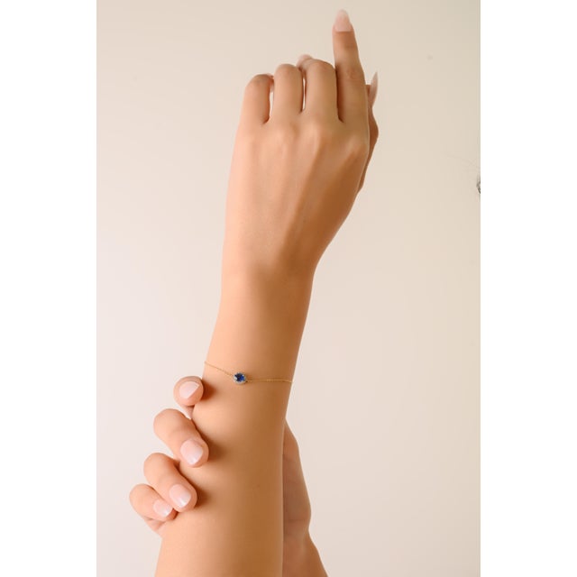 This bracelet features a 0.46 CT oval-cut blue sapphire, beautifully encircled by a halo of round brilliant- cut diamonds...