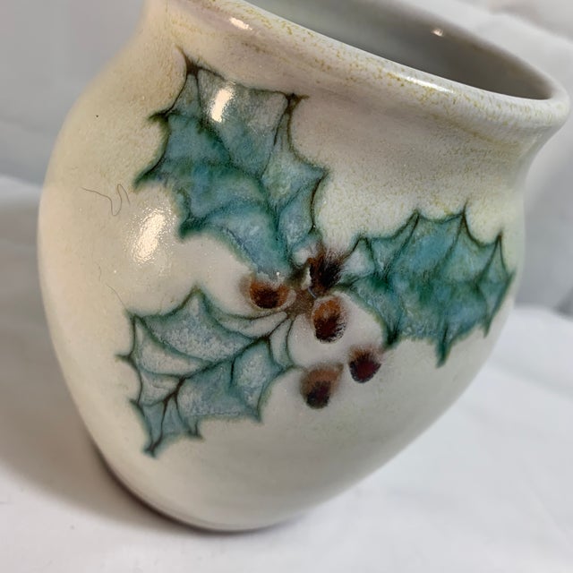 Offered here is a vintage studio pottery vase decorated with a hand-painted Christmas holly and berry motif. It features a...