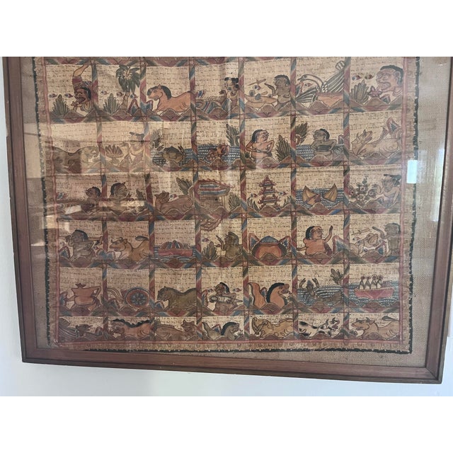 A striking and richly detailed framed Balinese narrative manuscript painting featuring dozens of hand-painted figural and...