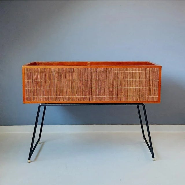 This planter, made of wood and covered with rattan, in typical 50s/60s style, rests on a heavy (approx. 6.5 kg) black...