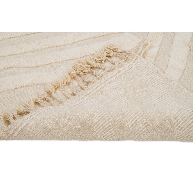 Refined hand-knotted wool rug showcasing a geometric pattern in a warm Ivory tone. Its intricate texture and timeless...