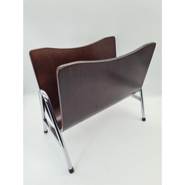 A unique magazine rack in the mid-century modern style, crafted from bent plywood and a chrome frame, dating from the...
