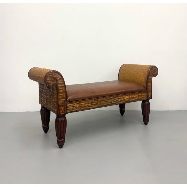 A substantial Pulaski upholstered bench featuring elegant neoclassical scroll arms, richly carved wood accents, and turned...